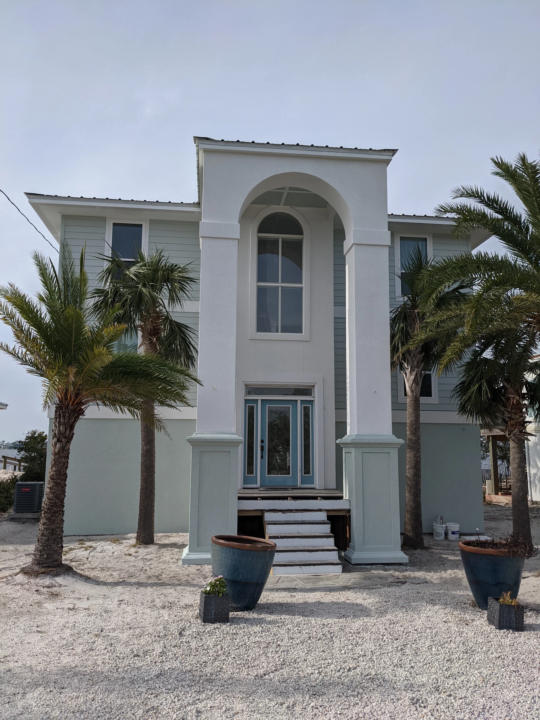 Tall white entrance with arches and palm trees