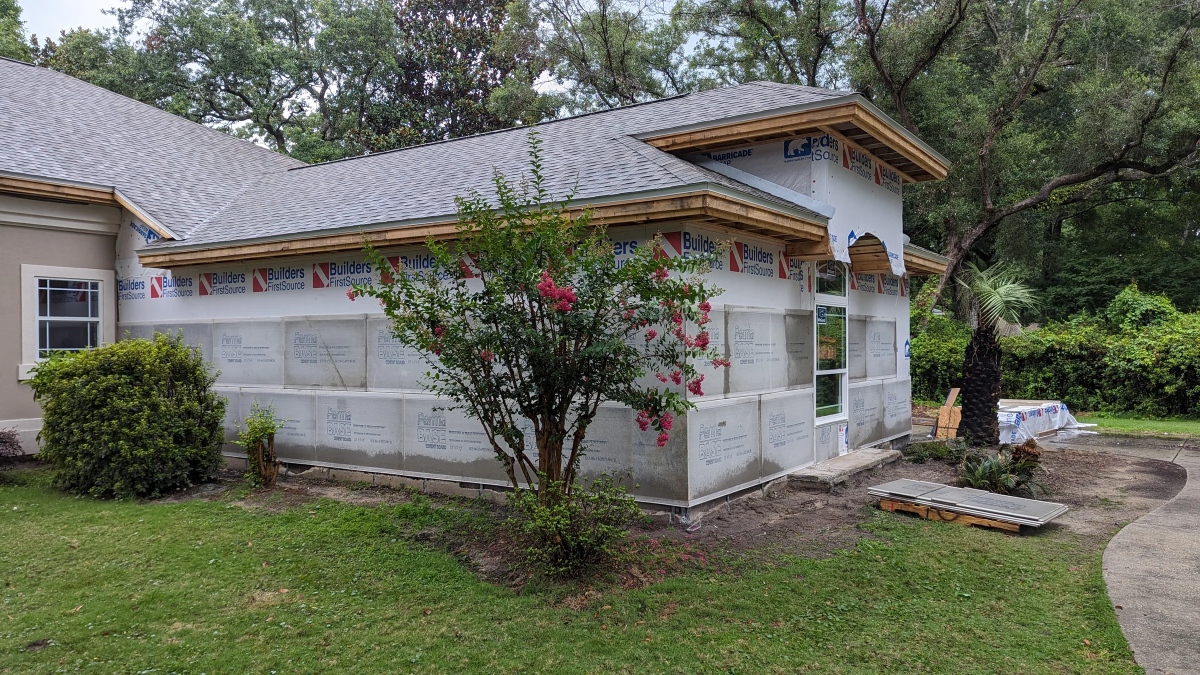 House with exposed exterior wrap and flowering tree