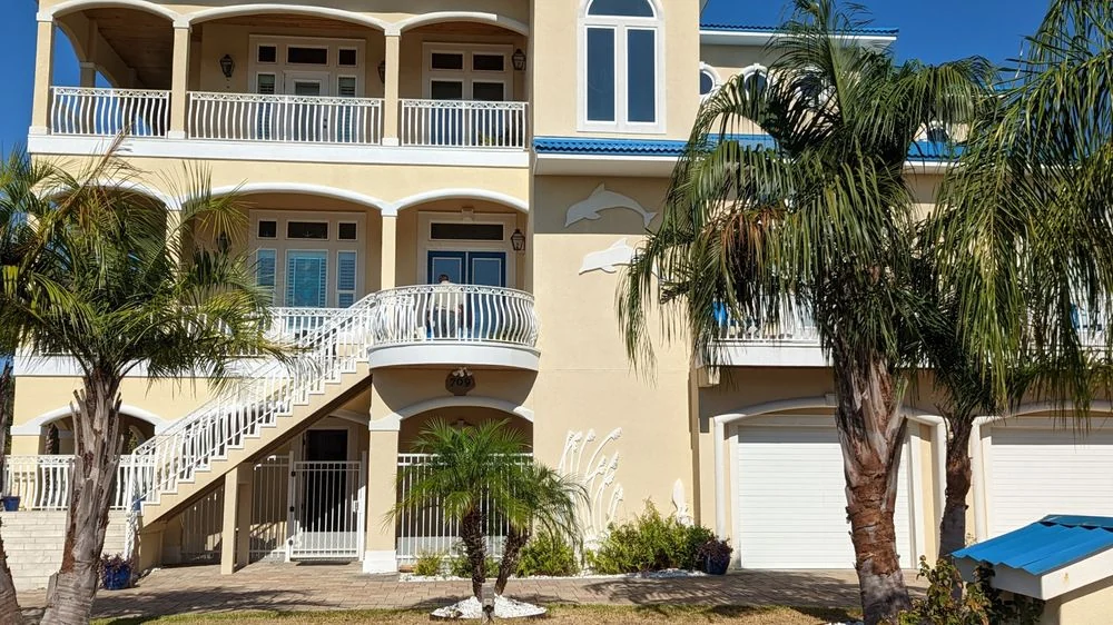 Large white house with balconies and palm trees