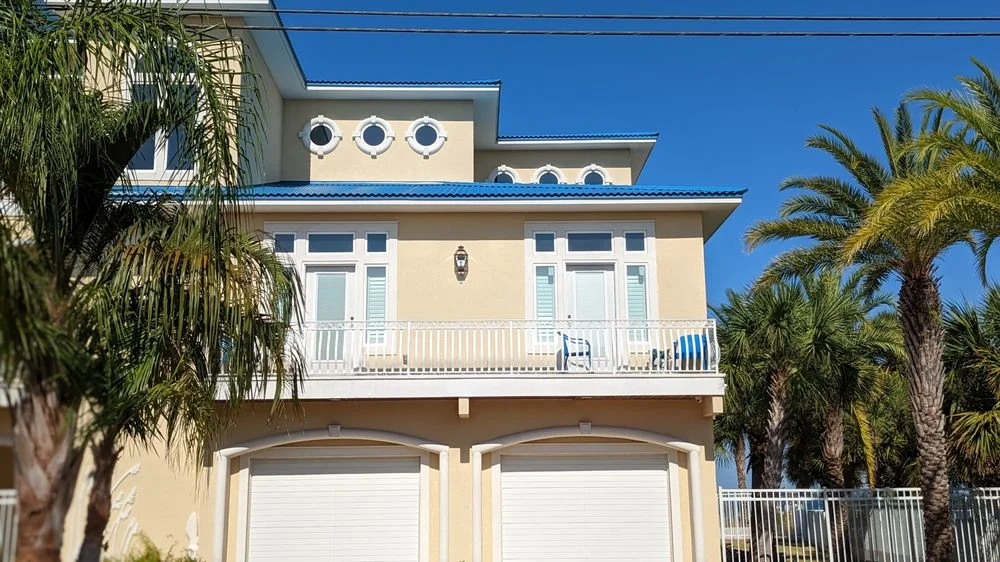 Cream-colored house with a double garage and palm trees